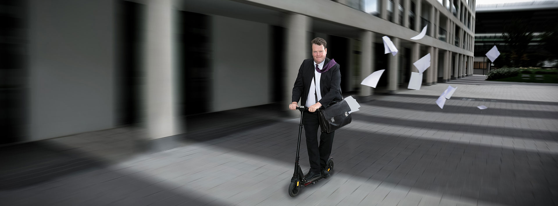 Mann mit Anzug auf Scooter und aktentasche
